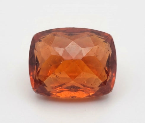 A cushion-cut faceted gemstone in a warm amber-orange hue, photographed against a plain white background.
