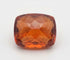 A cushion-cut faceted gemstone in a warm amber-orange hue, photographed against a plain white background.